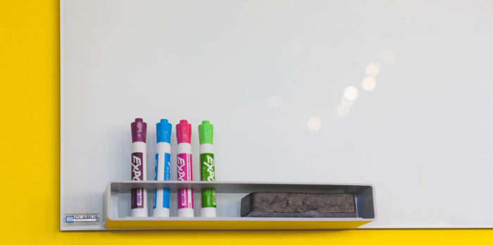 Unbeschriebenes Whiteboard mit 4 verschiedenfarbigen Markern im Halter